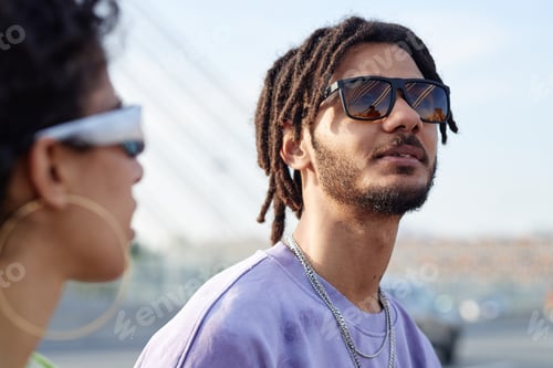 Vorschau: Junger Mann mit Sonnenbrille geht mit einem Freund der Generation Z im Freien spazieren