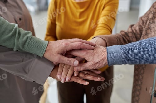 Preview: Close up of senior people stacking hands during support group session