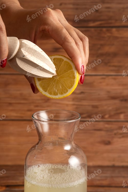 Preview: Female hand trying to make lemon juice on wooden background