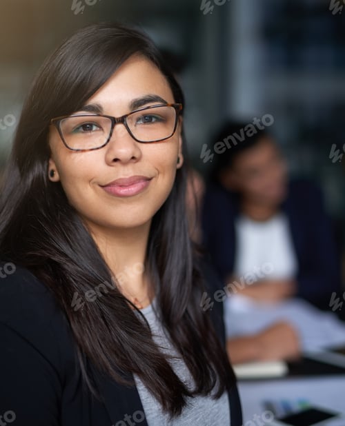 Preview: Portrait of a smiling young businesswoman in an office with colleagues in the background