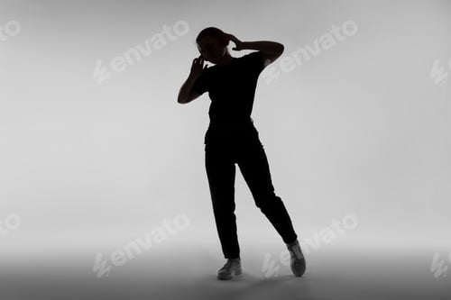 Preview: Silhouette of woman in headphones listening to music on grey background