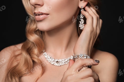 Vista previa: Beautiful young woman with elegant jewelry on dark background, closeup