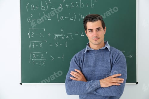 Preview: Young teacher near chalkboard with math formulas in classroom