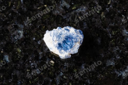 Preview: sample of raw blue spinel crystal on black granite