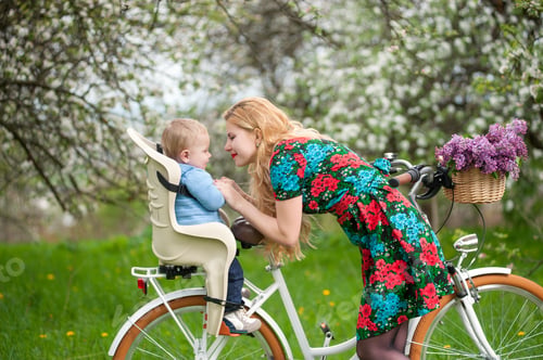 Preview: Blonde female with city bicycle with baby in bicycle chair