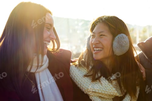 Preview: Chinese woman enjoying winter day with college friend outdoors. Young multiracial people laughing.
