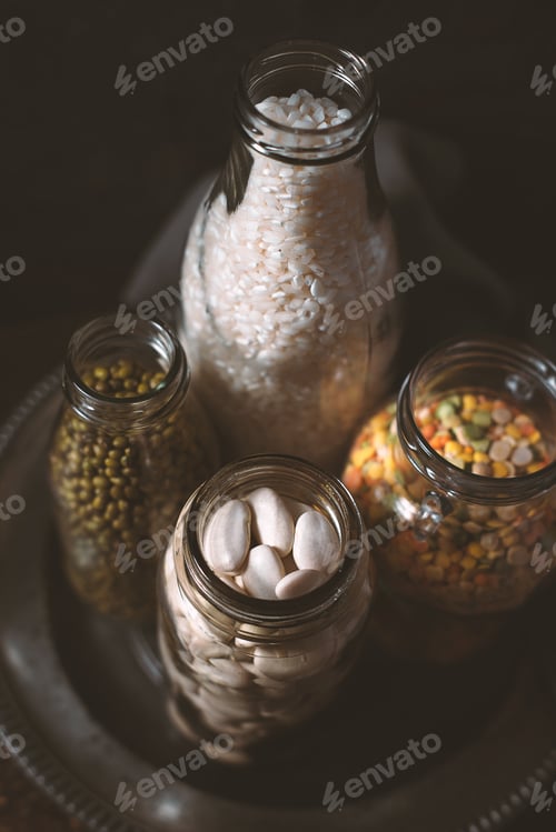 Preview: Lentils, white beans, rice in glass bottles side view