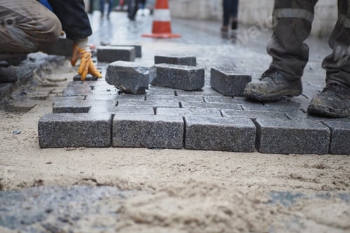 Preview: a worker laying concrete bricks on each other for building a new sidewalk