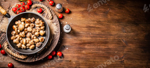 Preview: Frying pan with fried mushrooms on a wooden tray.