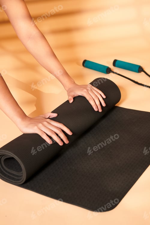 Preview: Woman Unrolling a Yoga Mat on Peach Surface