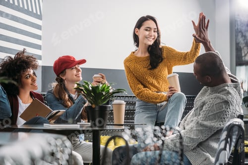 Preview: group of young friends spending time in cafe and giving high five