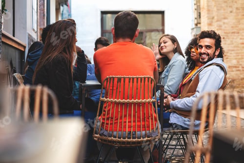 Preview: Multiethnic gGroup of young people sitting outdoors at cafe