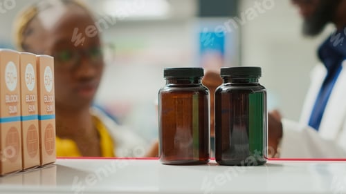 Preview: Drugstore worker showing vitamins pack to client