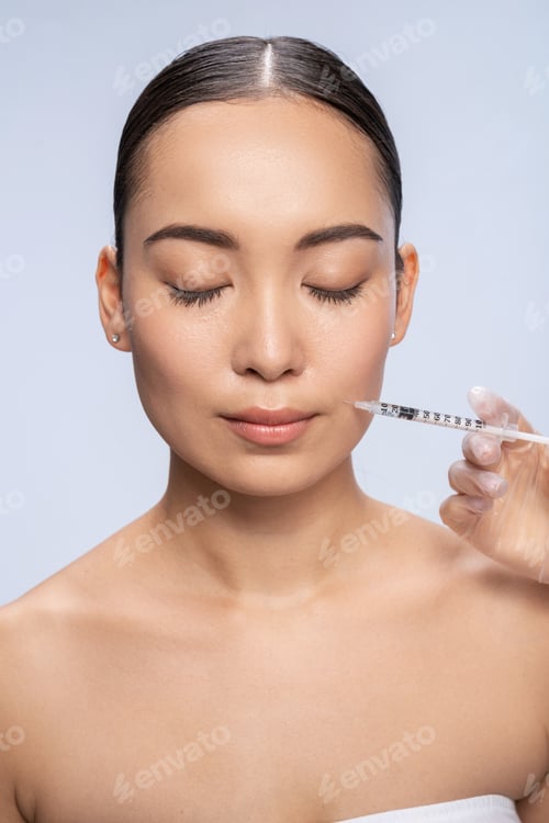 Preview: Asian lady having injection while posing in studio