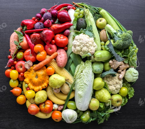 Preview: Various vegetables and fruits laid out in a circle on a dark background.