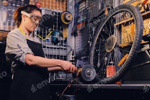 Preview: Female bicycle mechanic cutting and polish bike part.