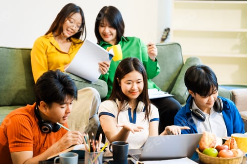 Preview: A group of young Asian college friends sitting on sofa at home,watching laptop,enjoying cheerful