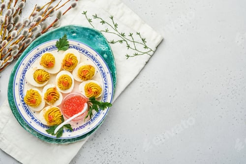 Preview: Stuffed eggs with red caviar and paprika on plate for appetizer easter table, top view, copy space.
