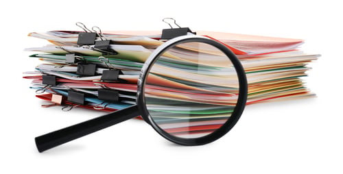 Preview: Stack of colorful folders with documents, binder clips and magnifying glass isolated on white
