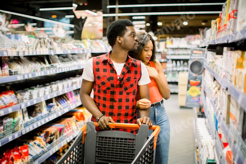 Preview: Family shopping for groceries in supermarket. Smiling african american couple with shopping trolley