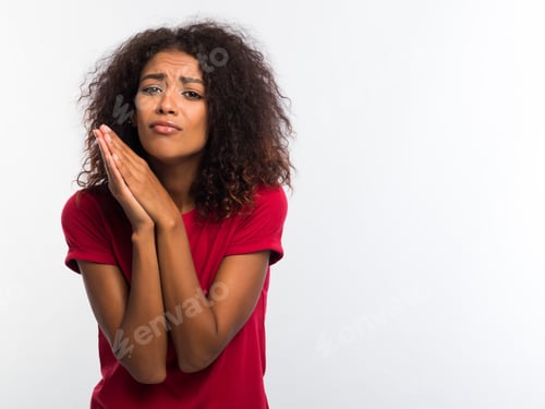 Preview: Attractive african woman in red t-shirt praying, begs over white background