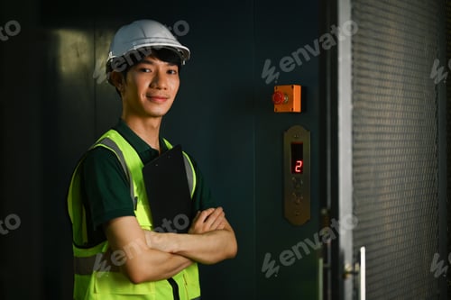 Preview: Confident male supervisor standing with arms crossed in industrial plant and smiling to camera