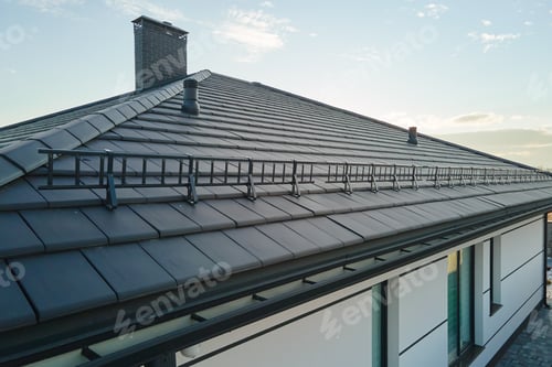Preview: Closeup snow guard for safety in winter on house roof top covered with ceramic shingles.