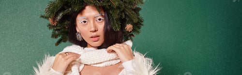 Preview: winter beauty, woman with white makeup and natural wreath adjusting scarf under falling snow, banner