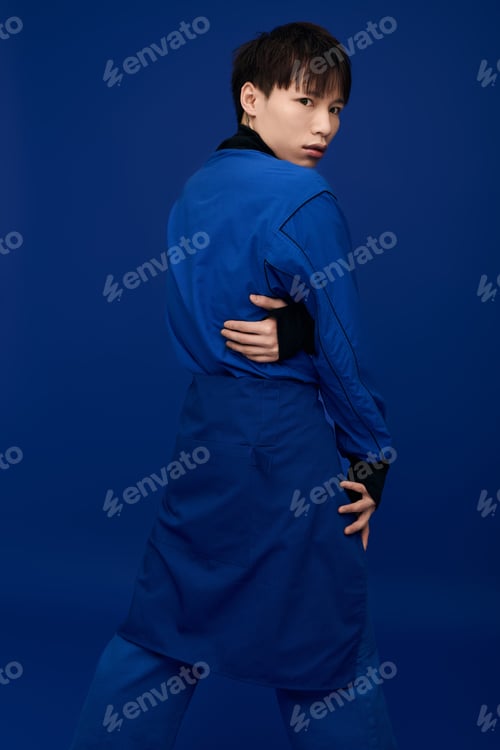 Preview: Young handsome asian man displaying confidence against a vivid blue background while posing