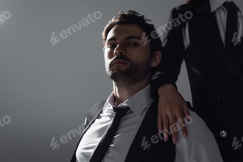 Preview: brunette man in white shirt and black tie looking at camera near woman isolated on grey