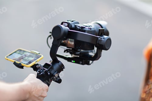 Preview: Operator using modern technology: stabilizer for camera and app on mobile phone for video streaming