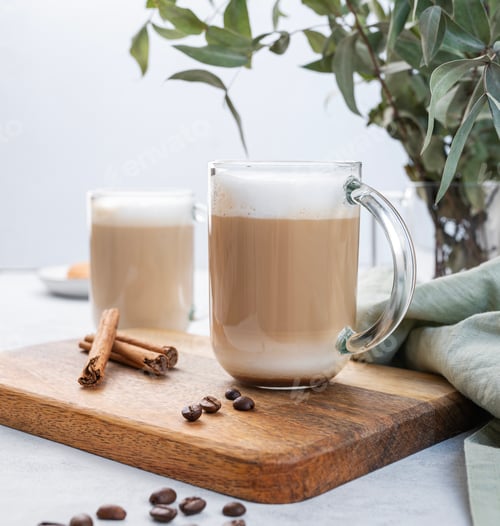 Preview: Two cappuccino or latte with milk foam in glasses on a wooden plate with coffee beans