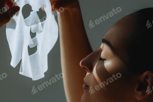 Preview: Young elegant woman in sunlight with white cosmetic mask in hand