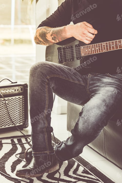 Preview: Fashionable handsome man playing guitar at home