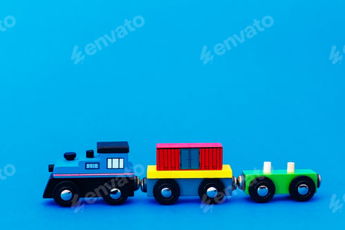 Preview: Colourful wooden toy train on blue background with copy space
