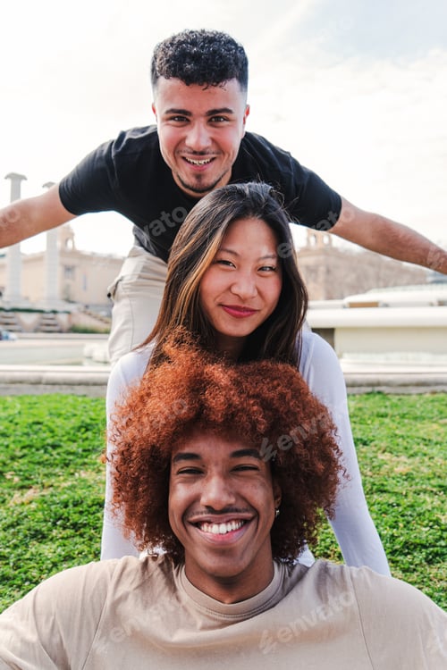 Preview: Vertical view of group of three multiracial young friends having fun and smiling looking at camera