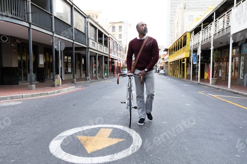 Preview: African American man walking beside his bike in the city street
