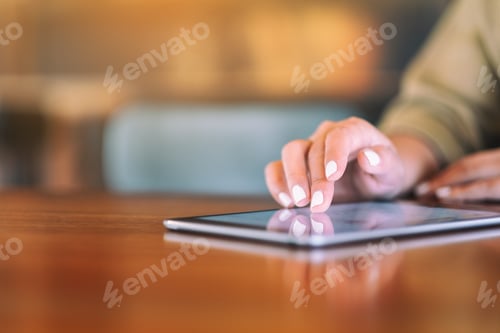 Preview: Closeup image of a woman pointing finger at tablet pc on wooden table