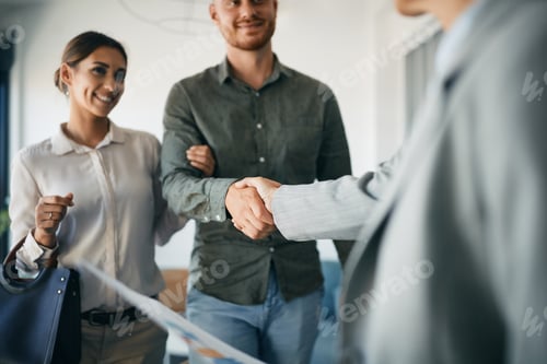 Preview: Close up of couple shaking hands with real estate agent in the office.