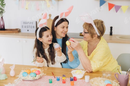 Preview: Three generations of women, happy mother with daughter and grandmother painting colorful eggs