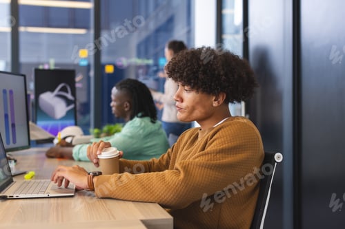 Preview: Diverse colleagues focusing on work in modern office using laptops