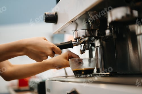 Preview: Cup and professional espresso machine pouring fresh coffee into a glass cup at cafe