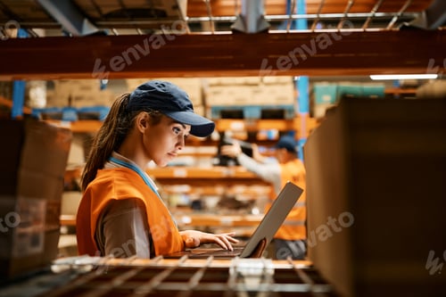 Preview: Female worker using laptop while working at distribution warehouse.