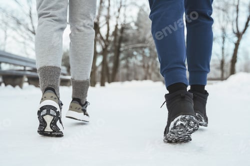 Preview: Two joggers feet during winter jogging in snowy city park