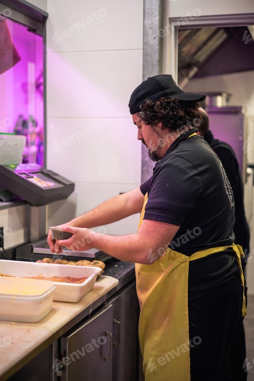 Preview: Butcher Crafting Chicken Nuggets in Kitchen, Sprinkling Parsley for Flavor Enhancement