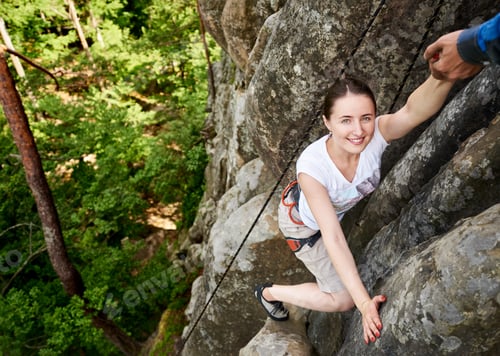 Preview: woman climbing rock trekking outdoors. Carefree hiker smiling her friend. Man helping to climb rock