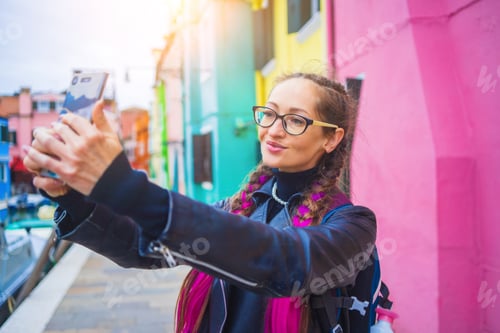 Preview: Traveler blogger taking selfie photo near colorful houses on Burano island in Venetian lagoon.