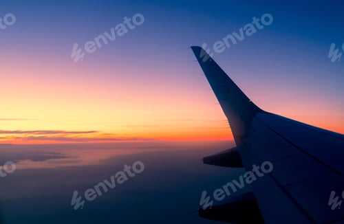 Preview: Wing of plane with sunrise skyline. Airplane flying in the sky. Scenic view from airplane window.