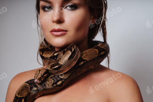 Preview: Beautiful woman with python snake elegantly slithering over her neck