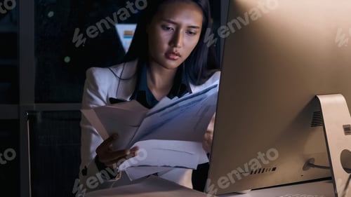 Preview: Stressed young Asian businesswoman working overtime at the office.